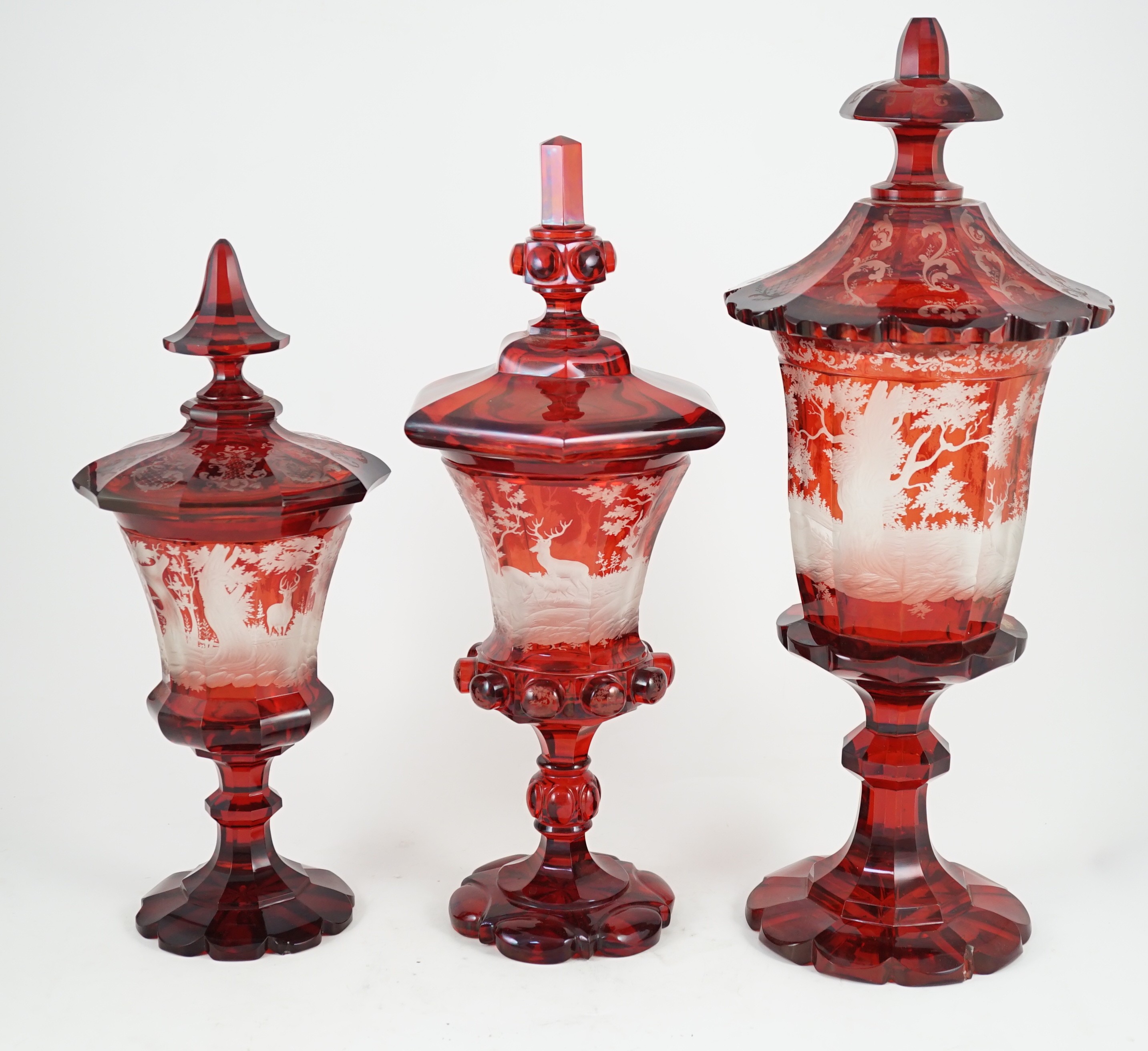 Three large Bohemian ruby stained glass goblets and covers, late 19th century, 38.5cm to 50.5cm high, rim chips